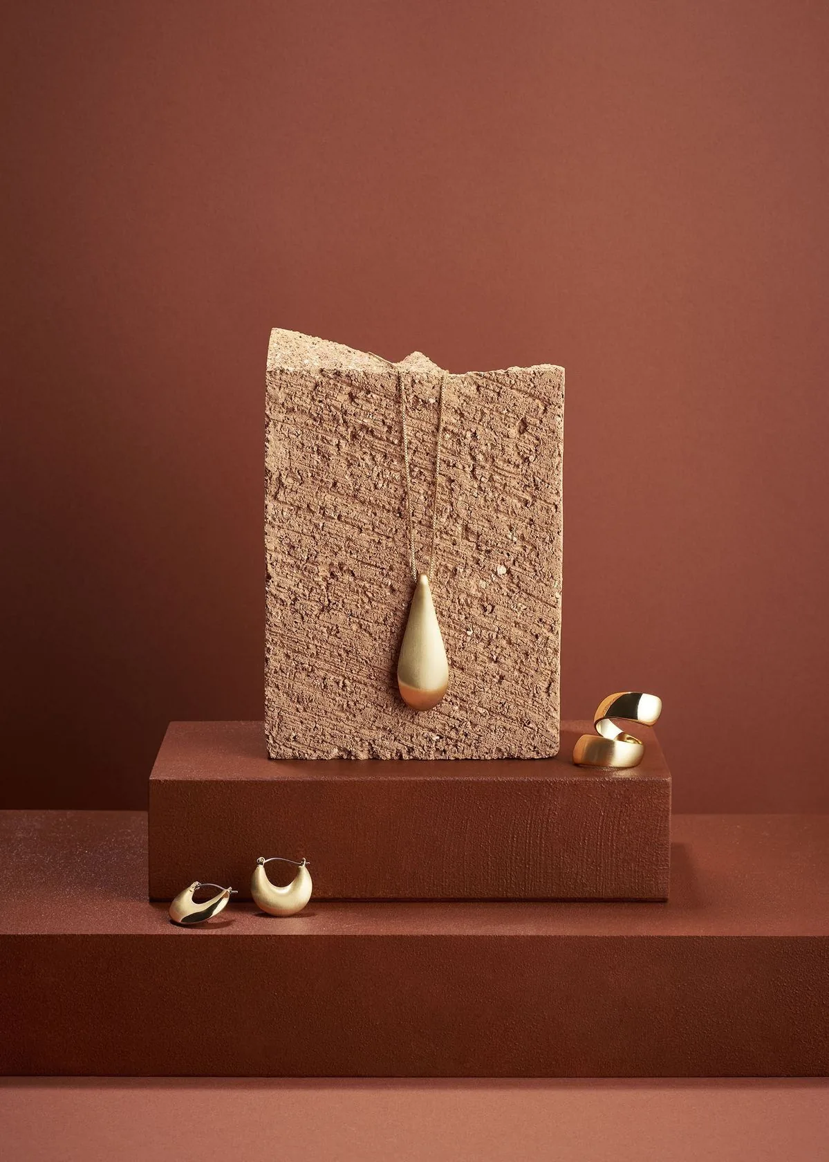 AI-generated luxury gold jewelry product photography on terracotta background by Automyze Studio Mumbai